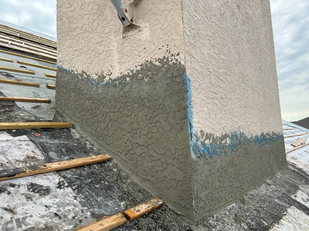 Professional chimney stucco repair showing a fresh base coat application on a residential roof in Fort Myers.